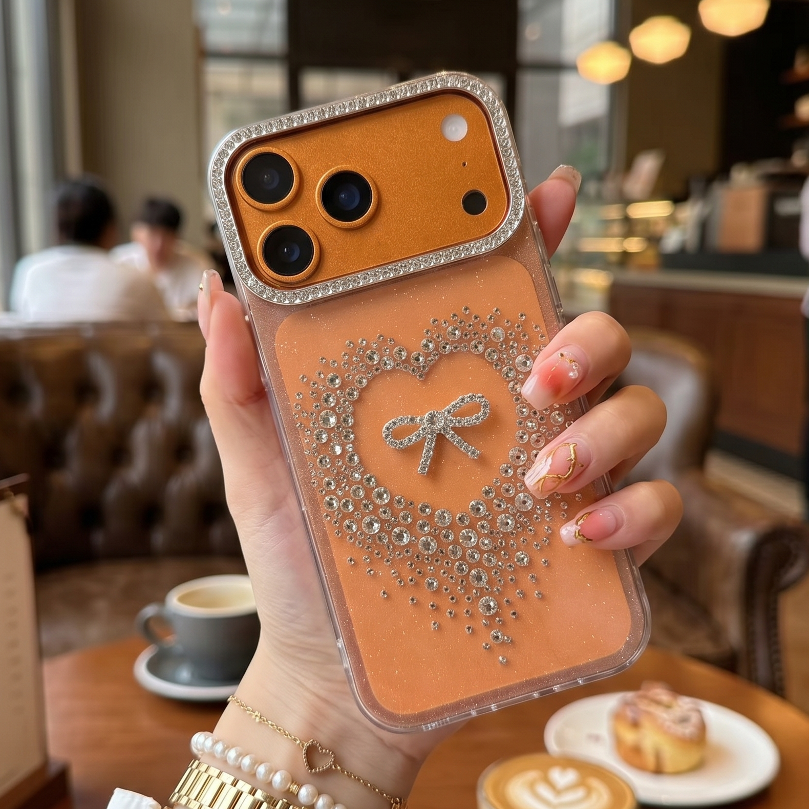 Person holding a phone case with decorative heart design in a cafe setting
